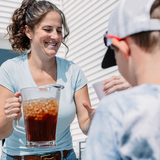 A woman pours a cold drink for children on a summer day
